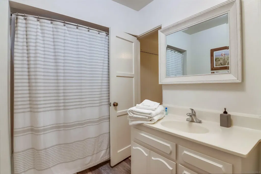 Upper-level bathroom with a white vanity, framed mirror and striped shower curtain